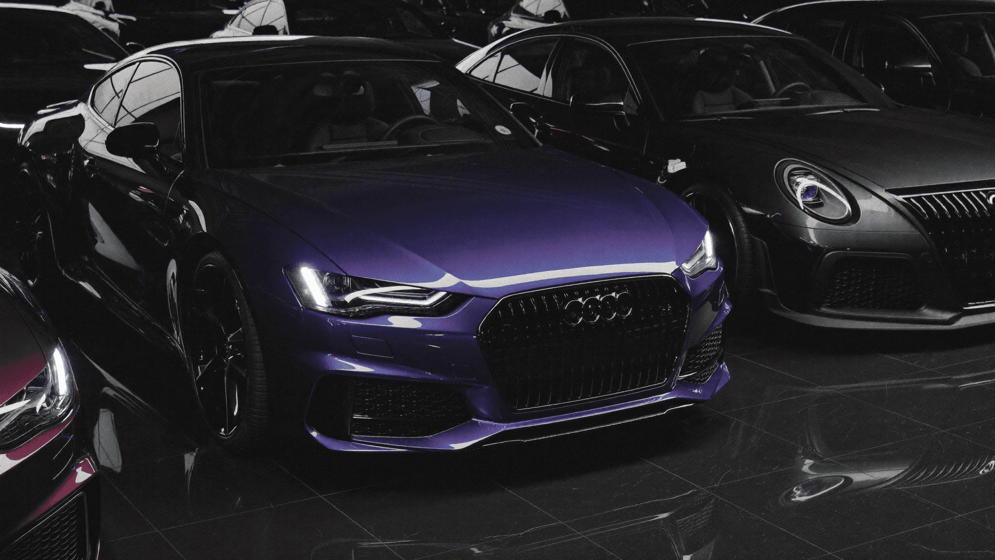 Exotic cars lined up in a dark, purple-lit showroom
