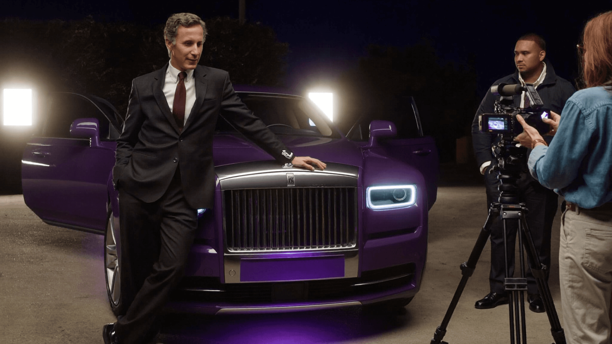 An owner's Rolls-Royce being filmed by a videographer at night